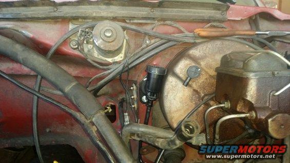 Red vehicle engine bay with brake master cylinder and vacuum booster