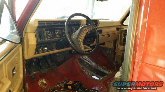 Interior view of a truck's dashboard and floor, showing pedals and a removed center console