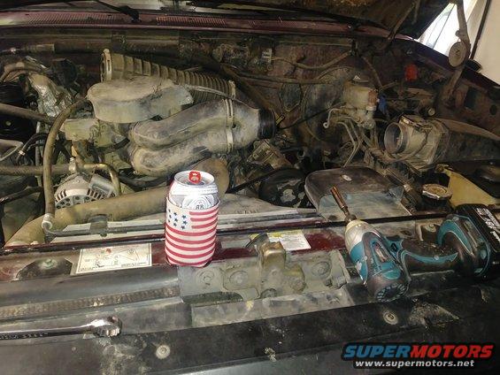 Engine bay with a beer koozie and tools on the radiator support