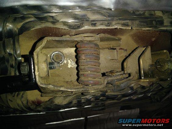 Door handle mechanism with a rusty spring and metal components, covered in dust