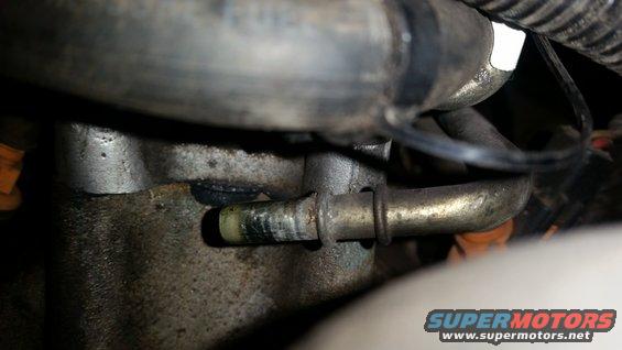 Close-up of a metal engine component with a hose attached and a clamp