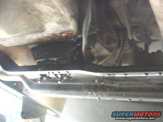 Underside of vehicle showing transmission and oil pan with leaks