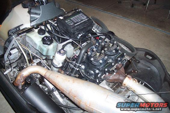 Snowmobile engine with triple cylinders and exhaust pipe. "900" is visible on engine covers