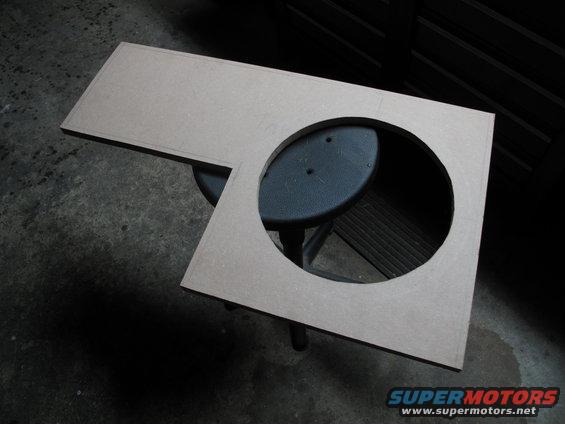 MDF panel with a large circular cutout, likely for a speaker, resting on a stool