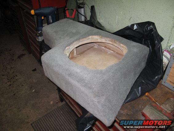 Gray carpeted subwoofer enclosure with circular cutout