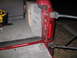 1994 Ford Bronco - The rear interior of a red SUV shows a custom subwoofer box and gray carpeting, with a yellow power tool visible.