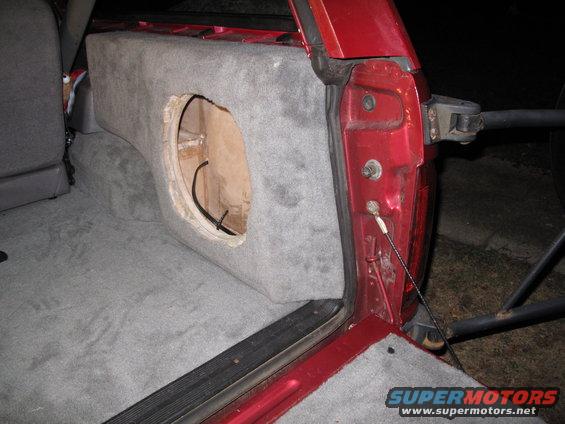 Custom carpeted subwoofer enclosure in red SUV cargo area