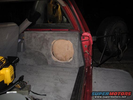 Red SUV interior with custom gray carpeted subwoofer enclosure and external spare tire mount