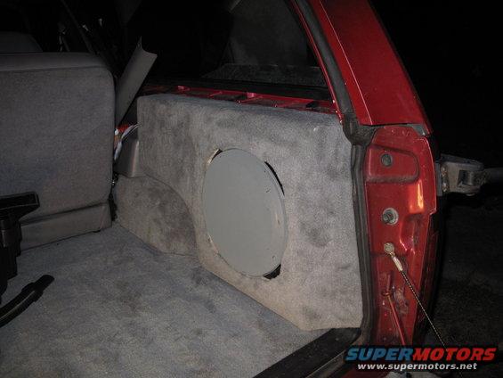 Red 1994 Ford Bronco interior with custom carpeted subwoofer enclosure and speaker cutout