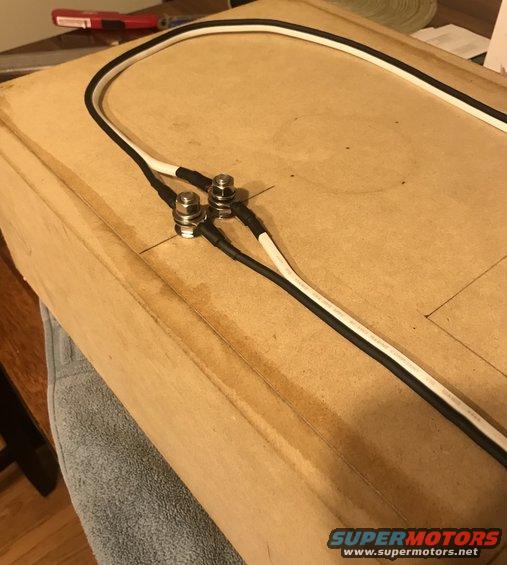 Two electrical connectors with black and white wires attached, mounted on a wooden surface