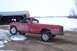 1988 Chevrolet Silverado 2500 - A red pickup truck sits in a snowy, rural setting next to a barn.