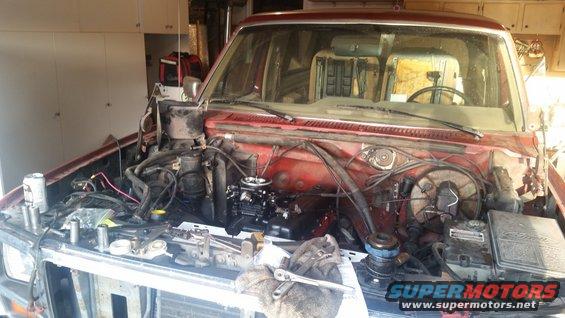Red SUV with hood open, engine compartment disassembled, tools on fender, Supermotors logo visible
