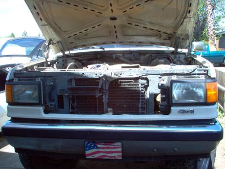 White Ford Bronco with hood open, showing engine bay. "4x4" emblem visible on fender. American flag license plate