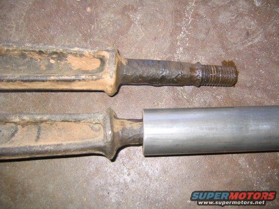 Two rusty metal rods, one with a threaded end, on a textured surface