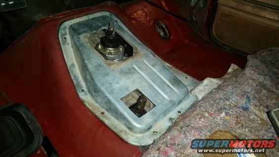 Interior shot of a vehicle's center console area with the transmission tunnel exposed, showing a shifter assembly and a hole for a transfer case lever