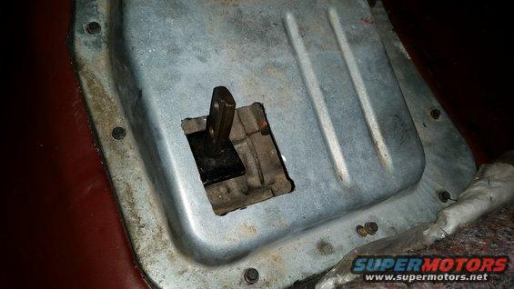 Close-up of a vehicle's transmission shifter linkage mechanism, showing the metal plate and lever