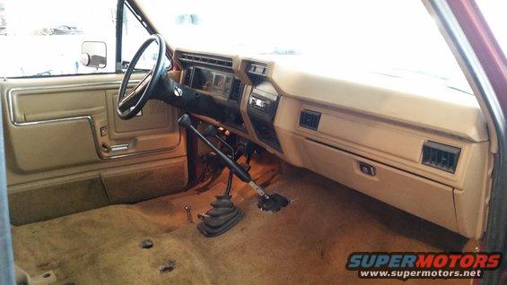 Tan interior of a 1980s Ford Bronco with a manual transmission and two shifters