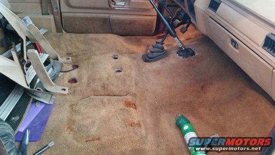 1985 Ford Bronco interior with carpet removed, showing floor pan and transmission tunnel