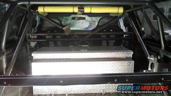 Vehicle interior showing roll cage, racing seats, and diamond plate toolbox