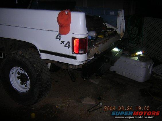 White pickup truck rear, 4x4 decal, orange cap on fender, 2004 date stamp