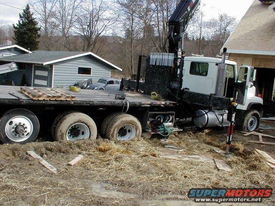 Crane truck stuck in mud with a flatbed trailer
