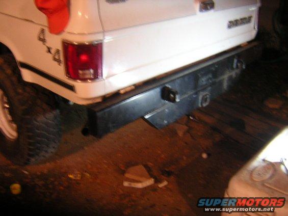 Rear of a white pickup truck with a black bumper and a red rag on the fender. Has 4x4 decal