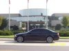 Dark sedan side view in front of modern building