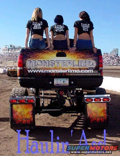 Monster truck with 'MONSTERLIMO' and 'F-350' on tailgate, three women sitting on the tailgate