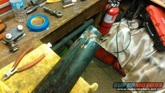 Metal pipe with blue weld marks, wire cutters, and blue tape on a workbench