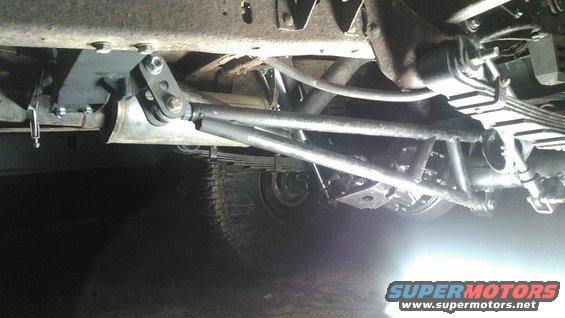 Underside view of a traction bar suspension modification on a vehicle