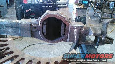 Modified rear axle housing on a workbench, with welding equipment in the background