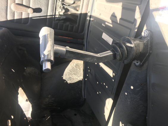 Close-up of a gear shifter mechanism with a silver knob and black rubber boot