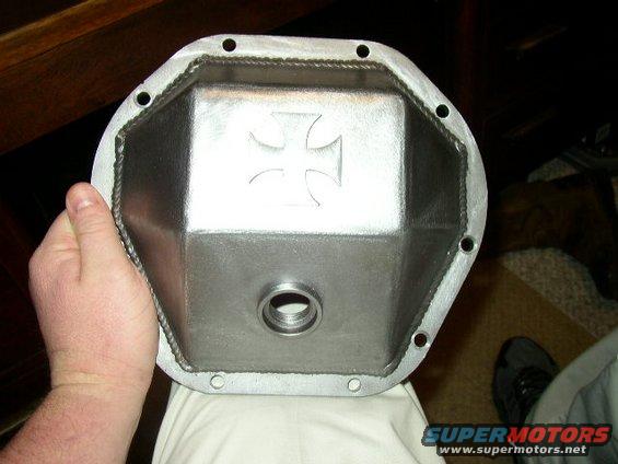 Hand holding a metal differential cover with an embossed Iron Cross