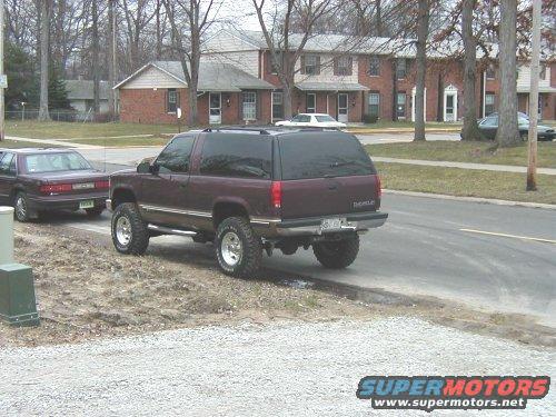 Maroon SUV, lifted, with off-road tires, viewed from the rear