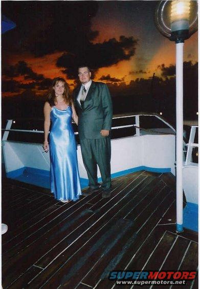 Couple dressed up on a boat deck with a sunset sky