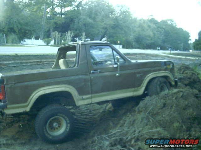Brown 1985 Ford Bronco stuck in dirt, side view