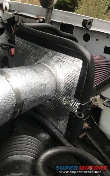 Engine bay shot showing an aftermarket air intake system with silver insulated tubing and a red air filter