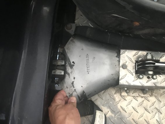 Close-up of a metal part with numbers stamped on it, held by a hand inside a vehicle