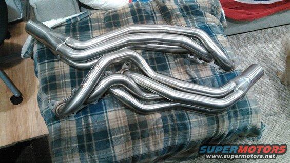 Pair of polished stainless steel exhaust headers on a plaid blanket