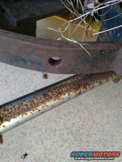 Close-up of heavily rusted metal frame and a chrome pipe with rust spots