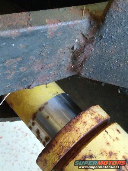 rusted metal frame with yellow and silver components, possibly part of a plow mechanism