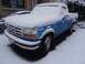 1994 Ford F-150 - A blue Ford F-150 truck is partially covered in snow, parked outdoors in winter.