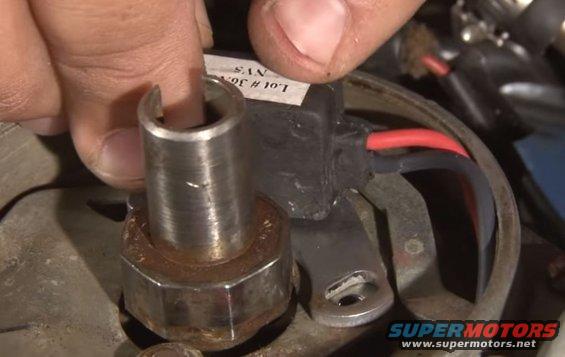 Distributor cap and rotor with red and black wires, a finger is pressing down on the rotor