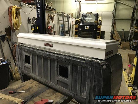 Truck bed with white Weather Guard toolbox. CAT loader in background