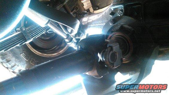 Underside of a vehicle showing a drive shaft connected to a differential, with leaf springs and a tire visible