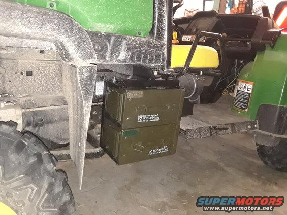 John Deere Gator utility vehicle with two stacked ammo cans on the side. Another green vehicle is partially visible
