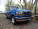 1994 Ford F-150 - A blue 1994 Ford F-150 pickup truck is parked outdoors on a paved surface covered with autumn leaves.