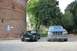1994 Ford F-150 - A blue 1994 Ford F-150 and a black car are parked outside a historic brick building.