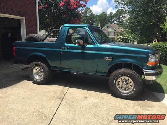 Teal 1996 Ford Bronco with spare tire in the bed, parked on a driveway