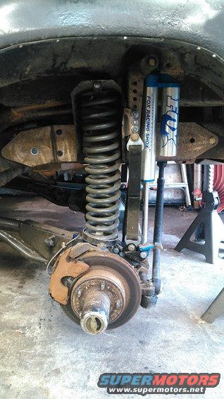 Front suspension with Fox Racing shocks and a large coil spring. Brake rotor and caliper visible